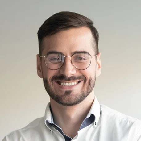 Ritratto di un uomo sorridente con occhiali e camicia bianca.
