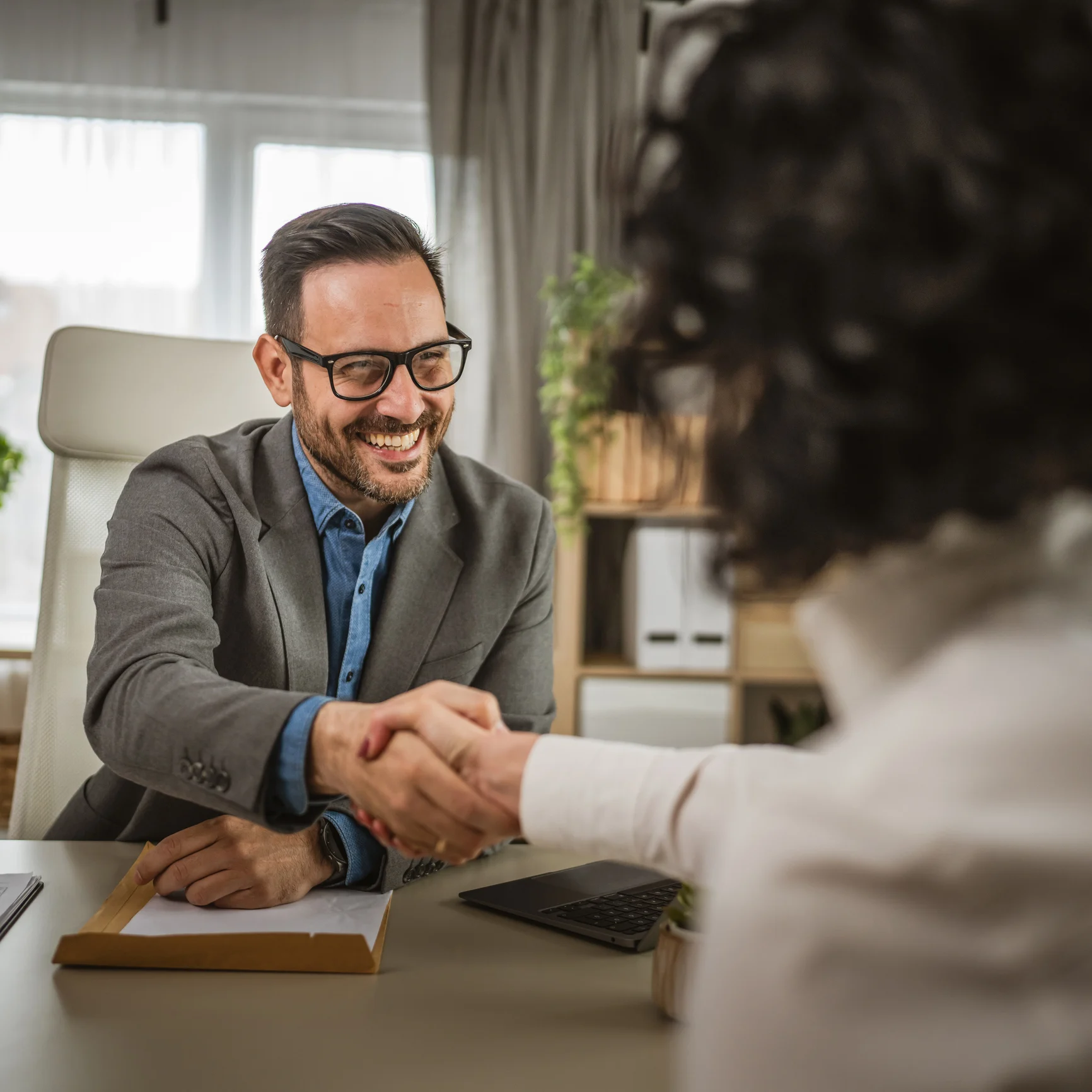 Recruiter und Bewerber schütteln sich während eines Vorstellungsgesprächs die Hand.