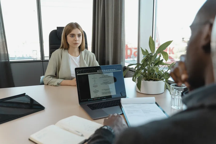 Un recruteur face à une candidate lors d’un entretien d’embauche, ordinateur portable et carnet de notes sur la table.