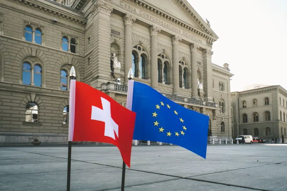 Un petit drapeau suisse et un petit drapeau européen plantés devant le Palais fédéral à Berne.